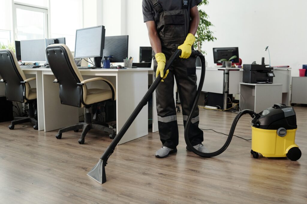 Young male staff of cleaning company in black uniform and yellow gloves